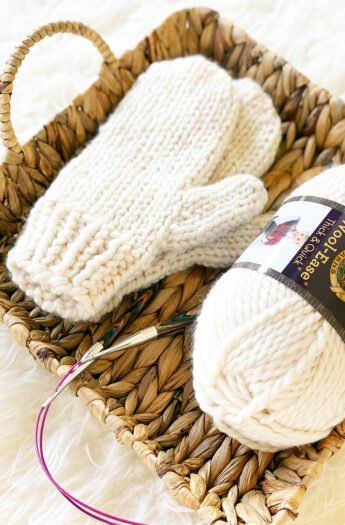 knitted mittens with yarn in a basket